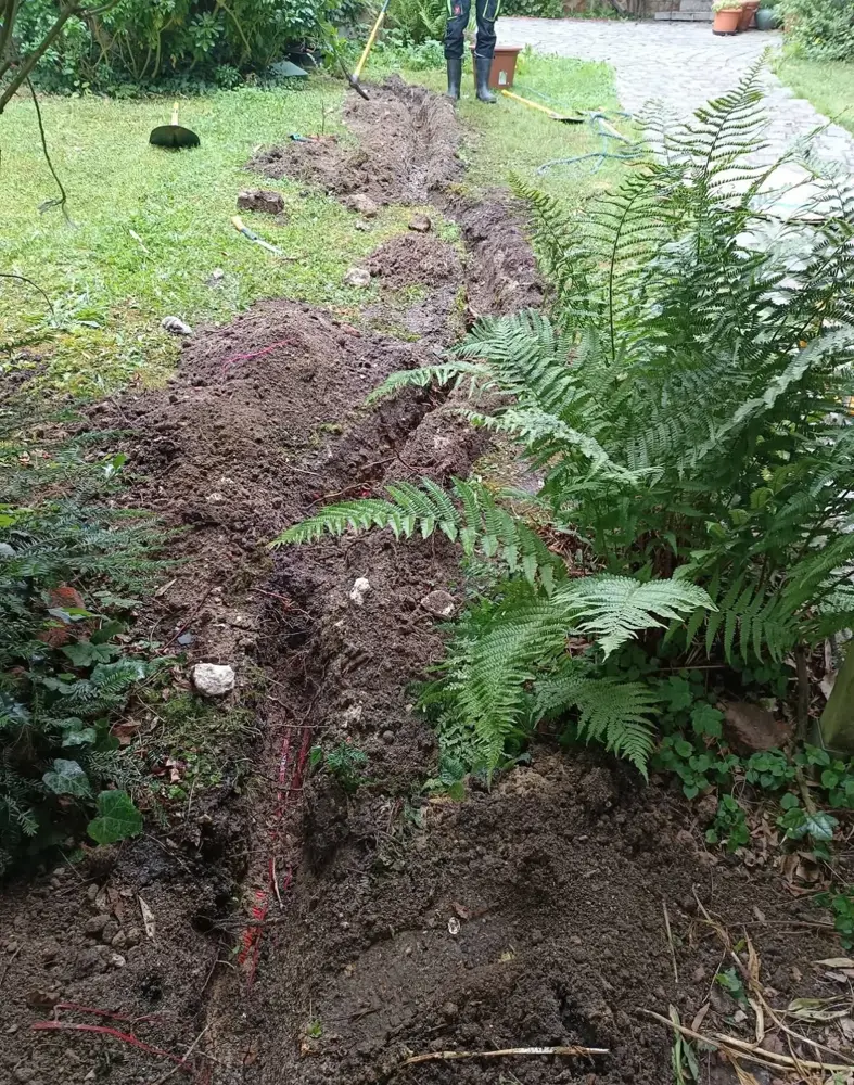 Tranchée creusée dans un jardin pour passer le câble d'alimentation de la borne