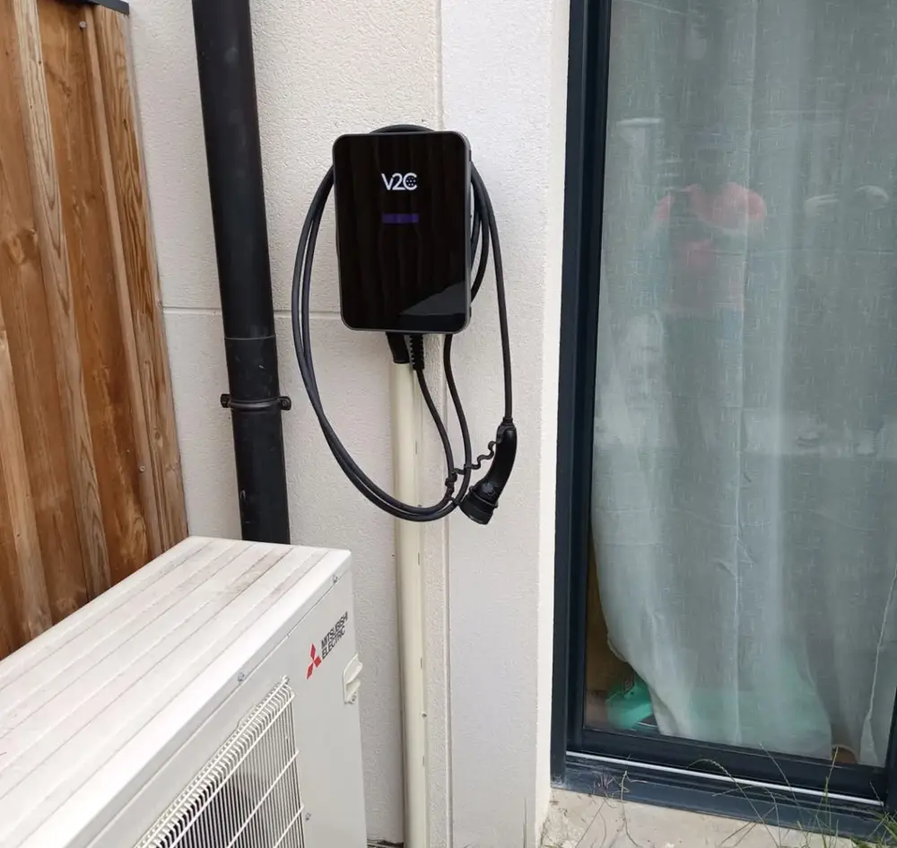 Borne V2C installée sur maison neuve à côté d'une pompe à chaleur