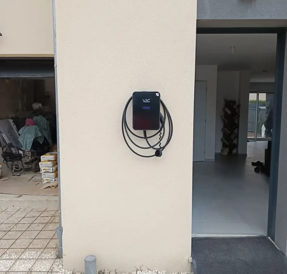 Borne V2C posée sur un pilier entre garage et entrée de maison